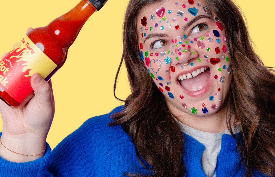 Yellow crate filled with fresh produce including kale, broccoli, oranges, apple, lemon, lettuce, and a bottle of honey on a blue and white checkered floor.